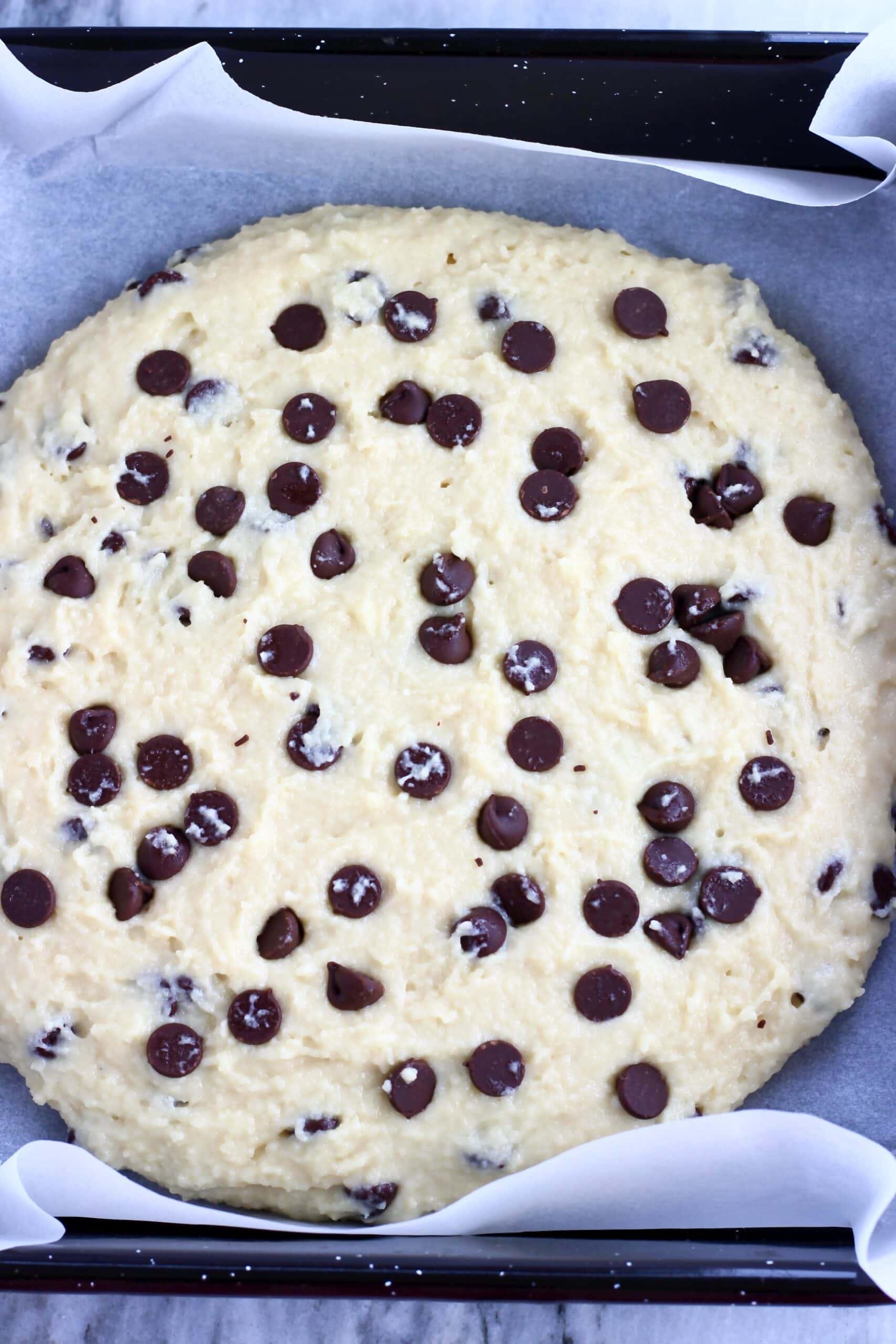 Raw gluten-free vegan chocolate chip scones dough in a circle on a baking tray lined with baking paper