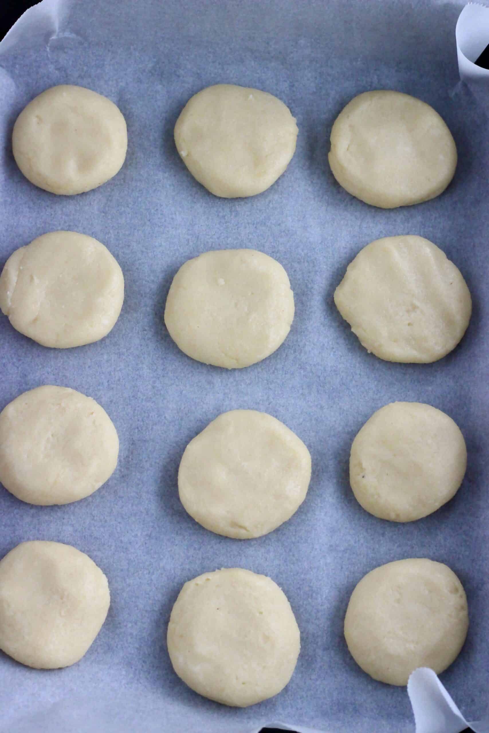 12 round vegan cookie dough patties on a baking tray lined with baking paper