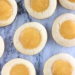 Several vegan lemon thumbprint cookies on a marble background