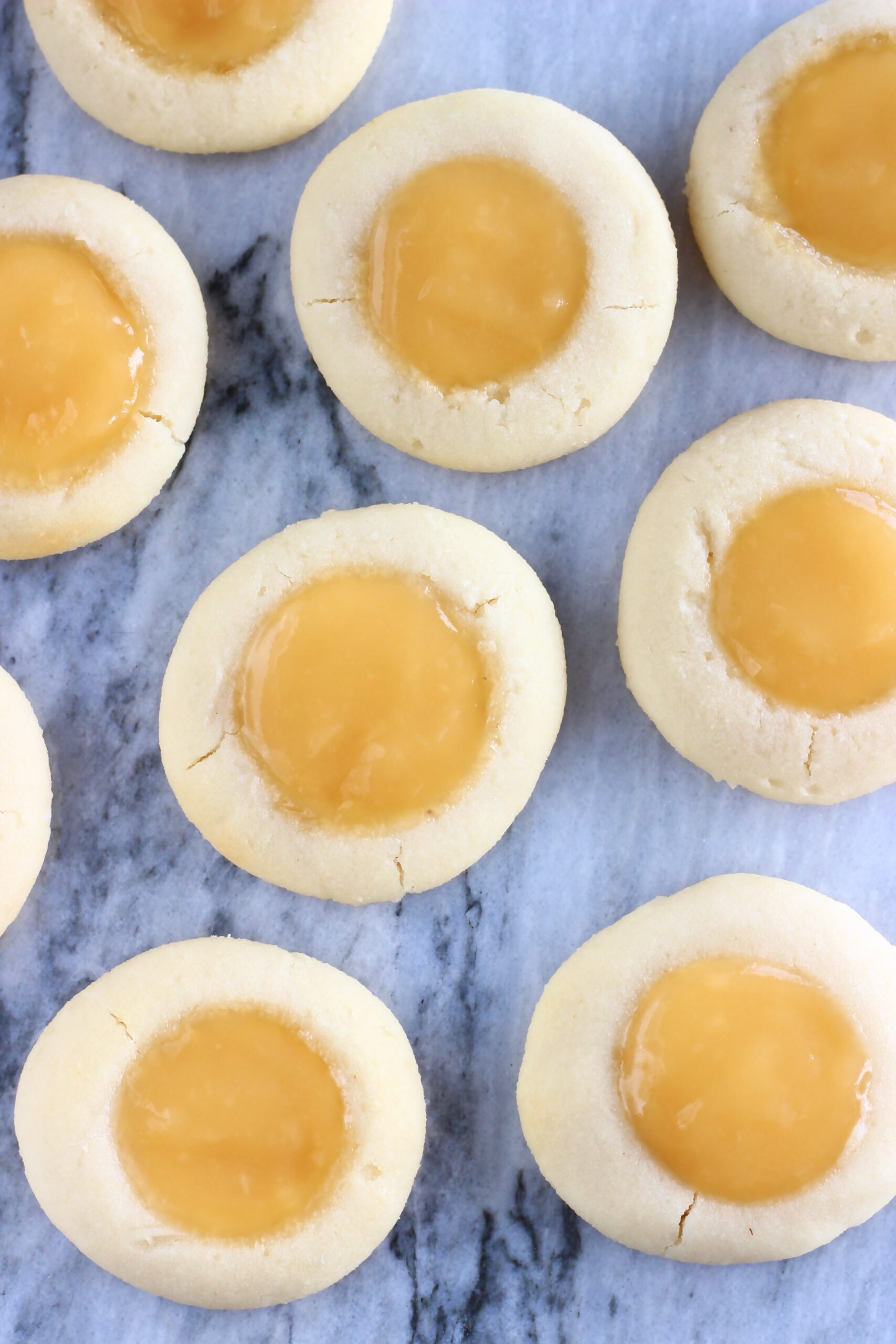 Several vegan lemon thumbprint cookies on a marble background