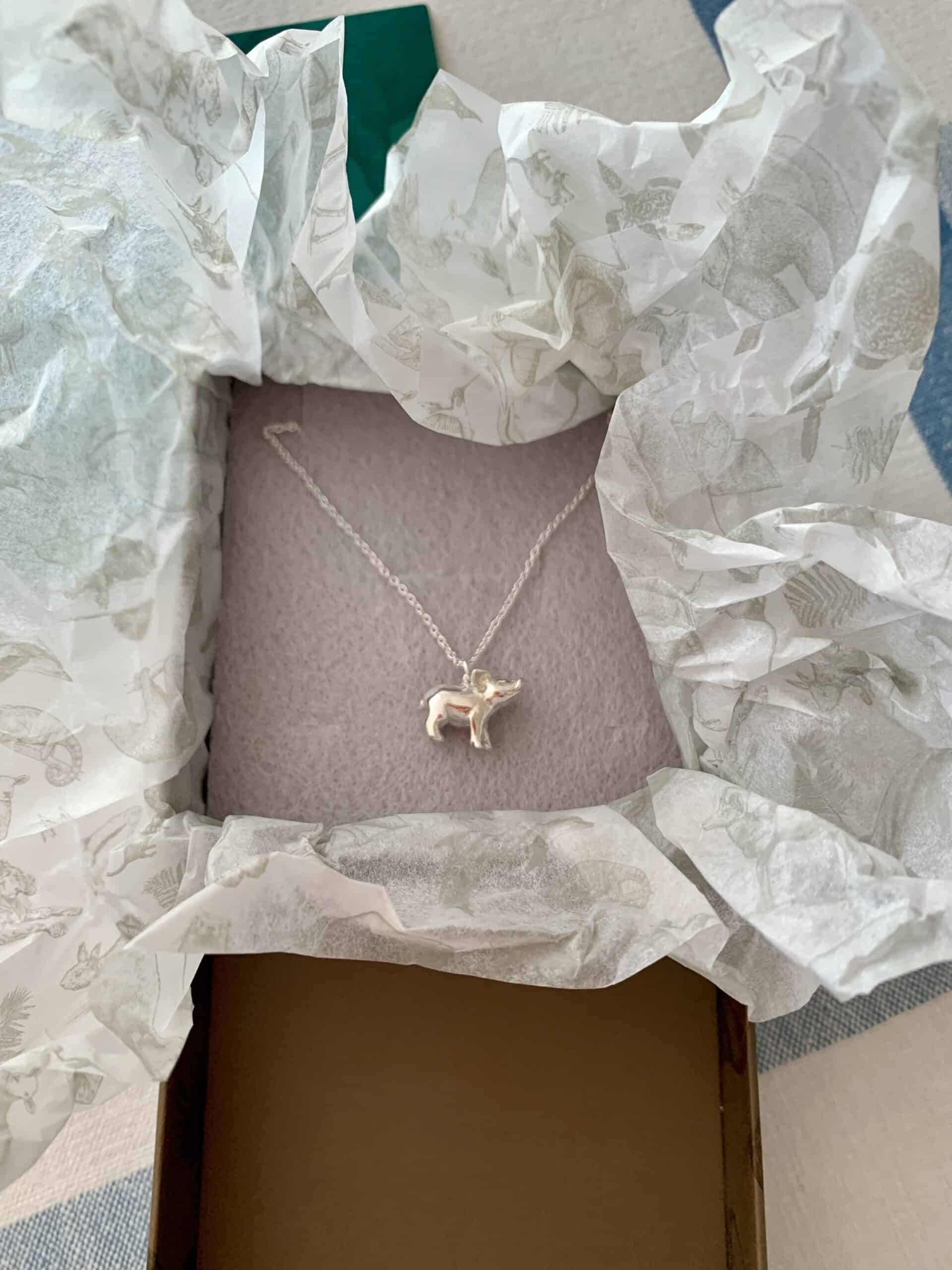 A Jana Reinhardt silver piglet necklace in a box
