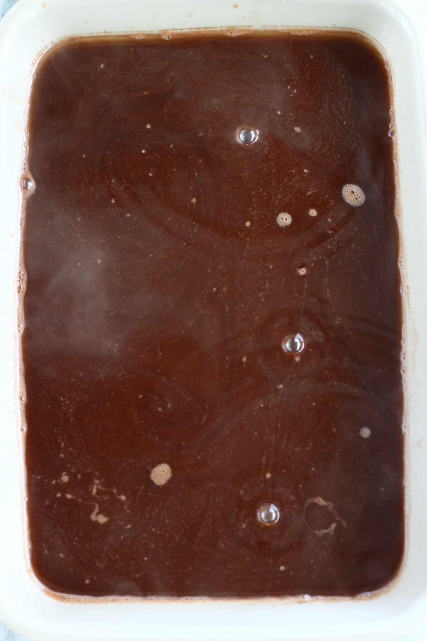 Vegan chocolate self-saucing pudding batter covered with hot water in a rectangular baking dish