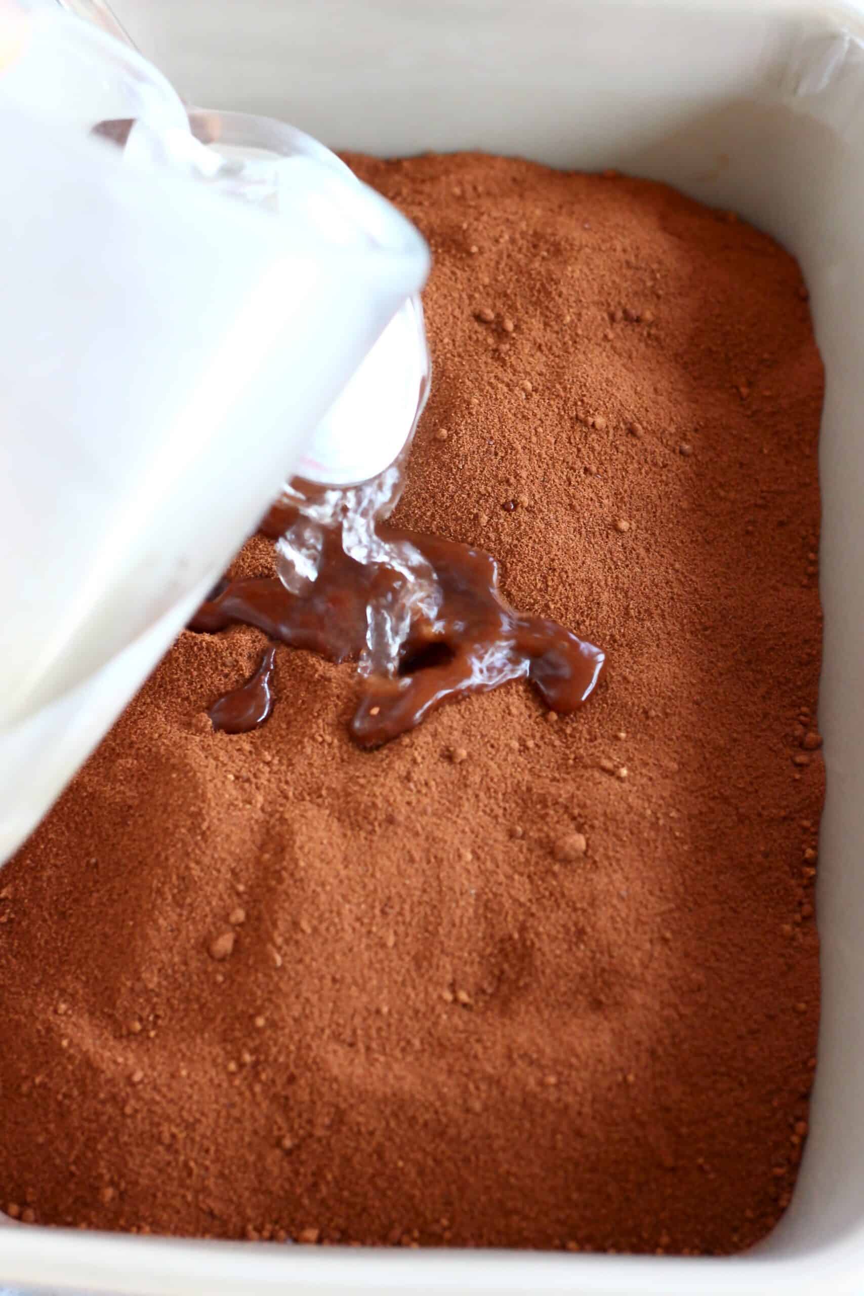 Hot water being poured over raw vegan chocolate fudge pudding batter in a baking dish