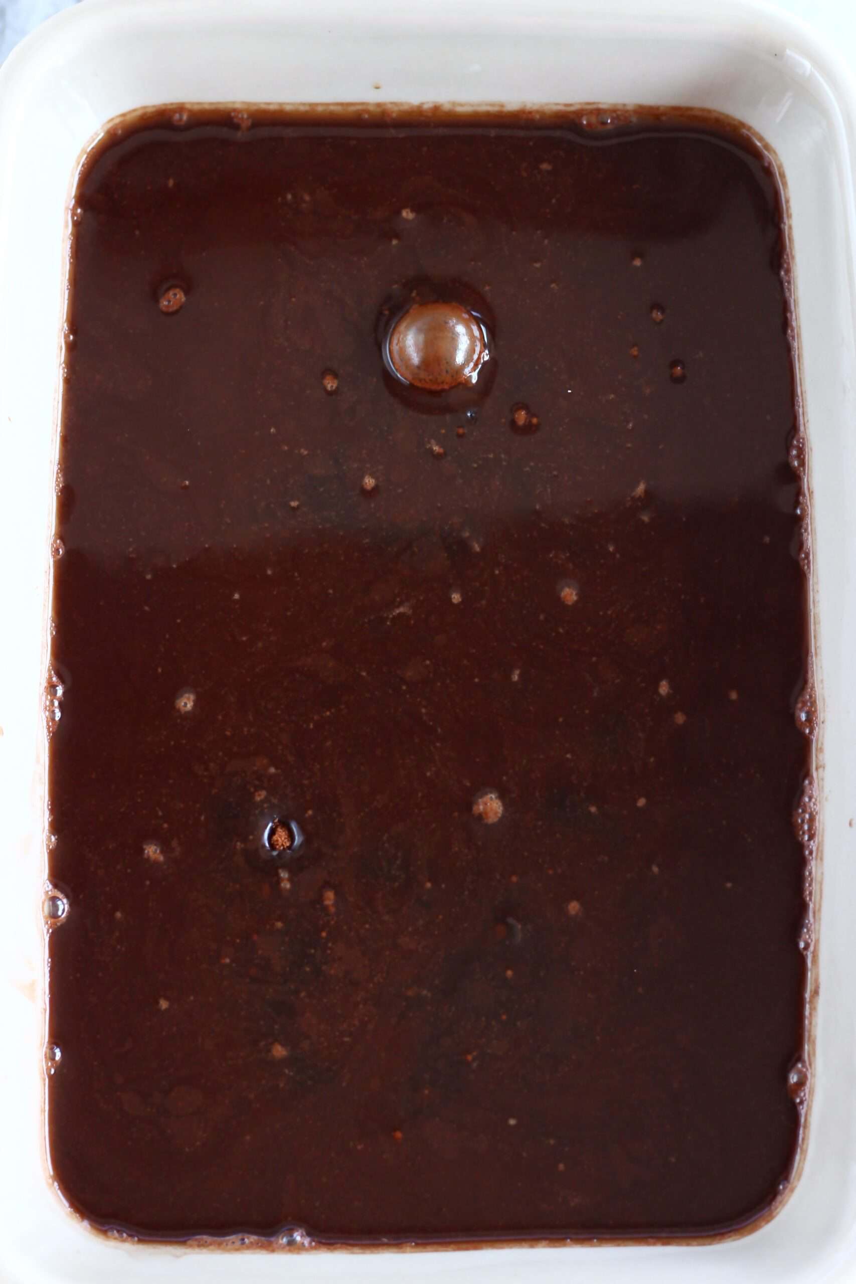 Raw vegan chocolate fudge pudding with hot water in a rectangular baking dish