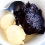 Vegan chocolate fudge pudding in a bowl with two scoops of vanilla ice cream and a spoon