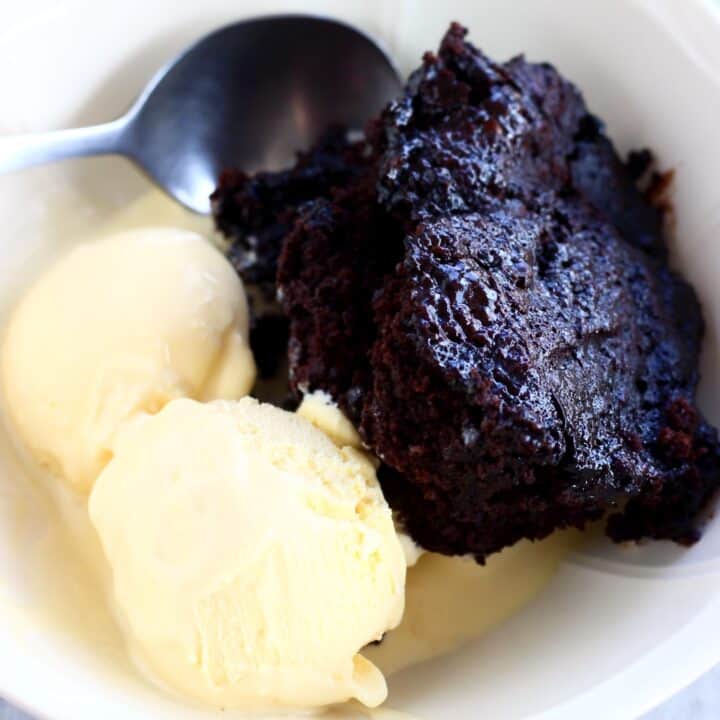 Vegan chocolate fudge pudding in a bowl with two scoops of vanilla ice cream and a spoon