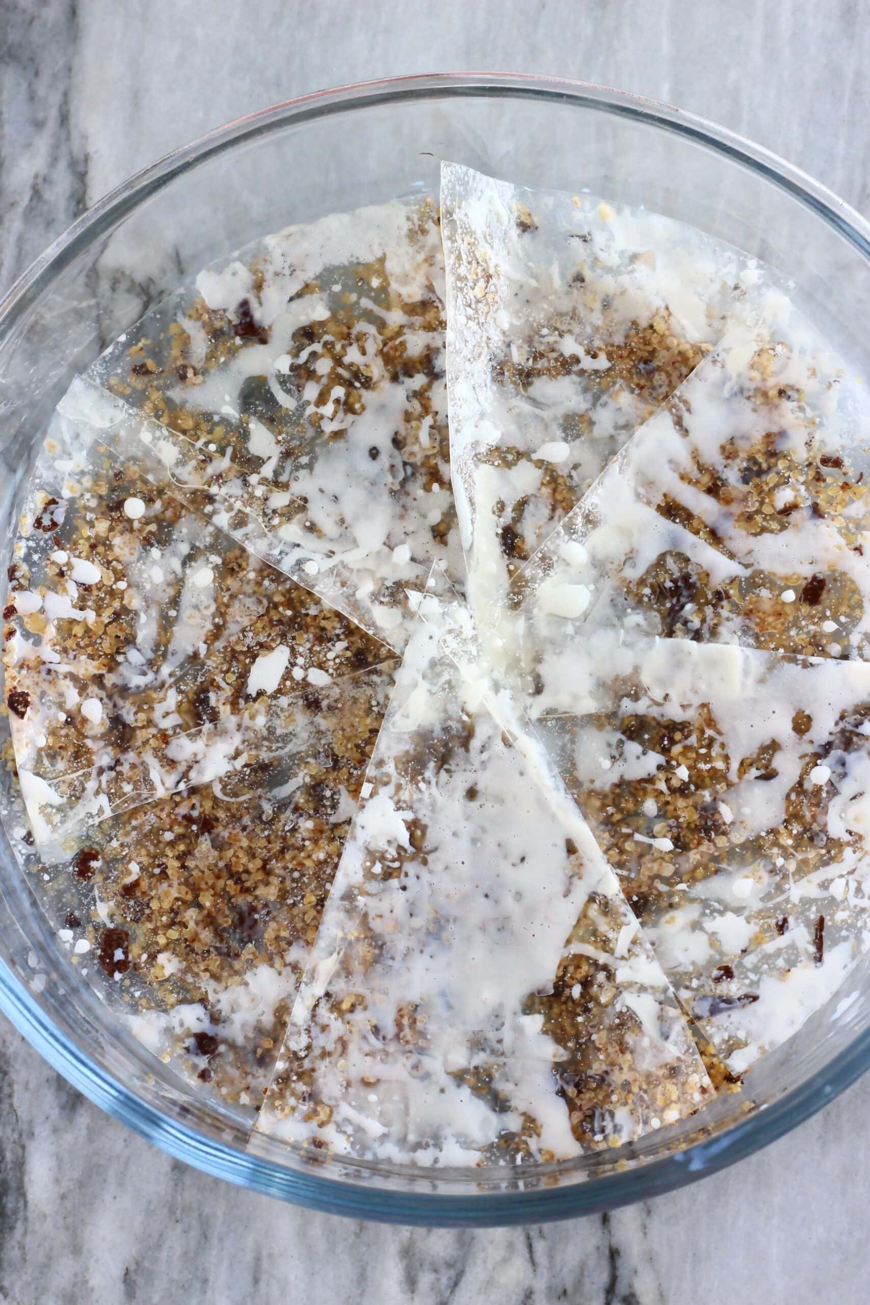 Blended nuts and chocolate mixture covered with milk-soaked rice paper sheets in a round baking dish