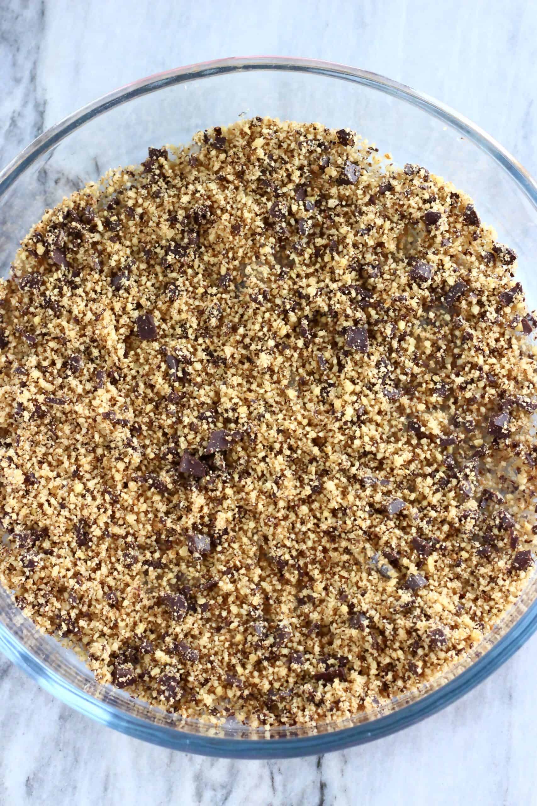 Blended nuts and chocolate mixture scattered over rice paper sheets in a round baking dish