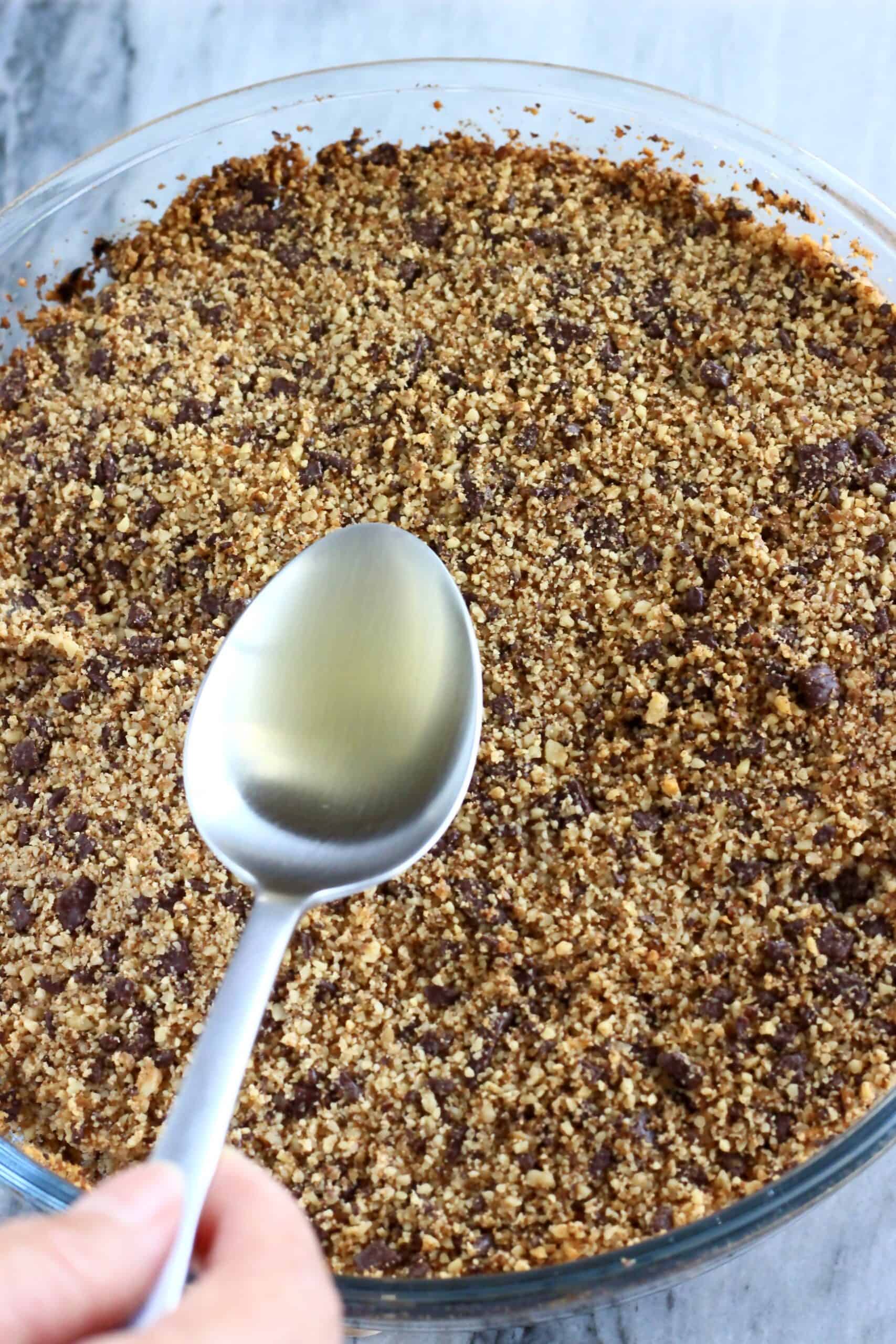 A spoon pouring syrup over gluten-free vegan chocolate baklava in a round baking dish