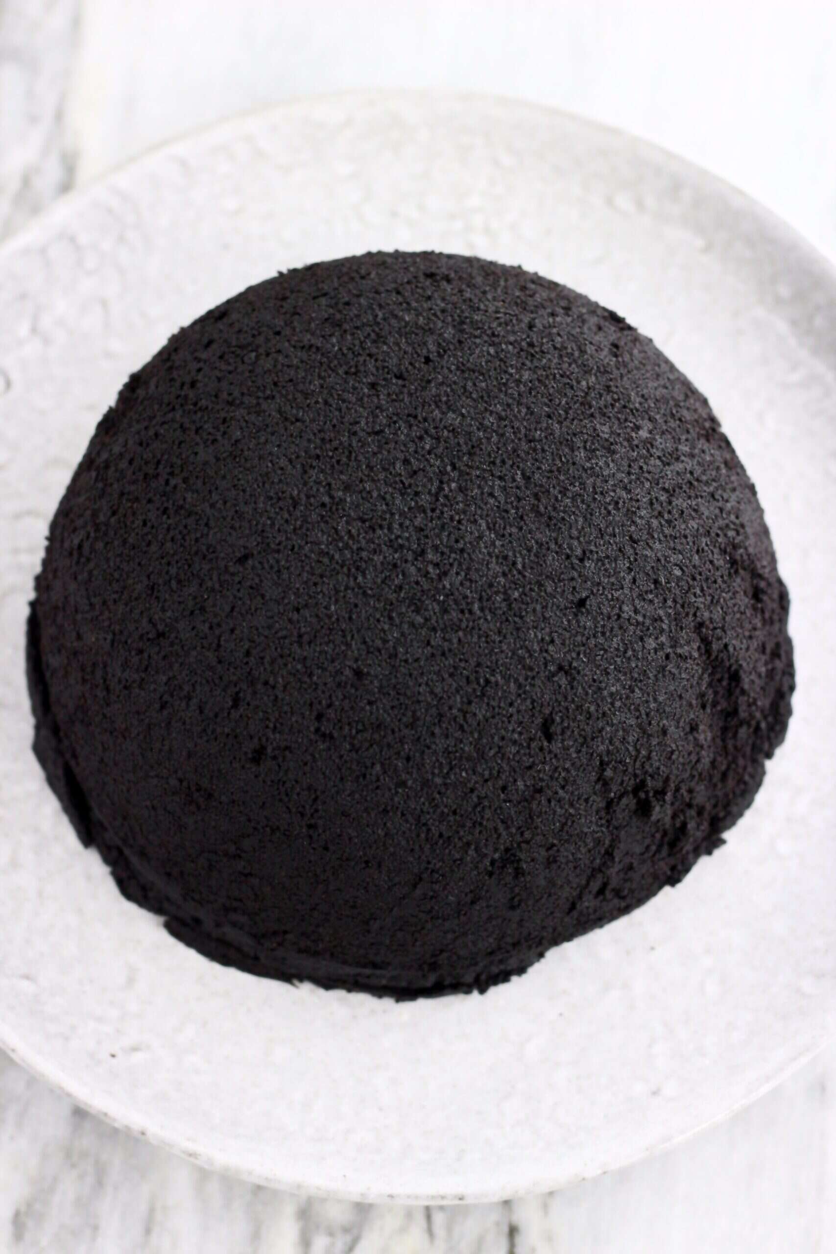 A cooked vegan chocolate Christmas pudding turned out onto a plate