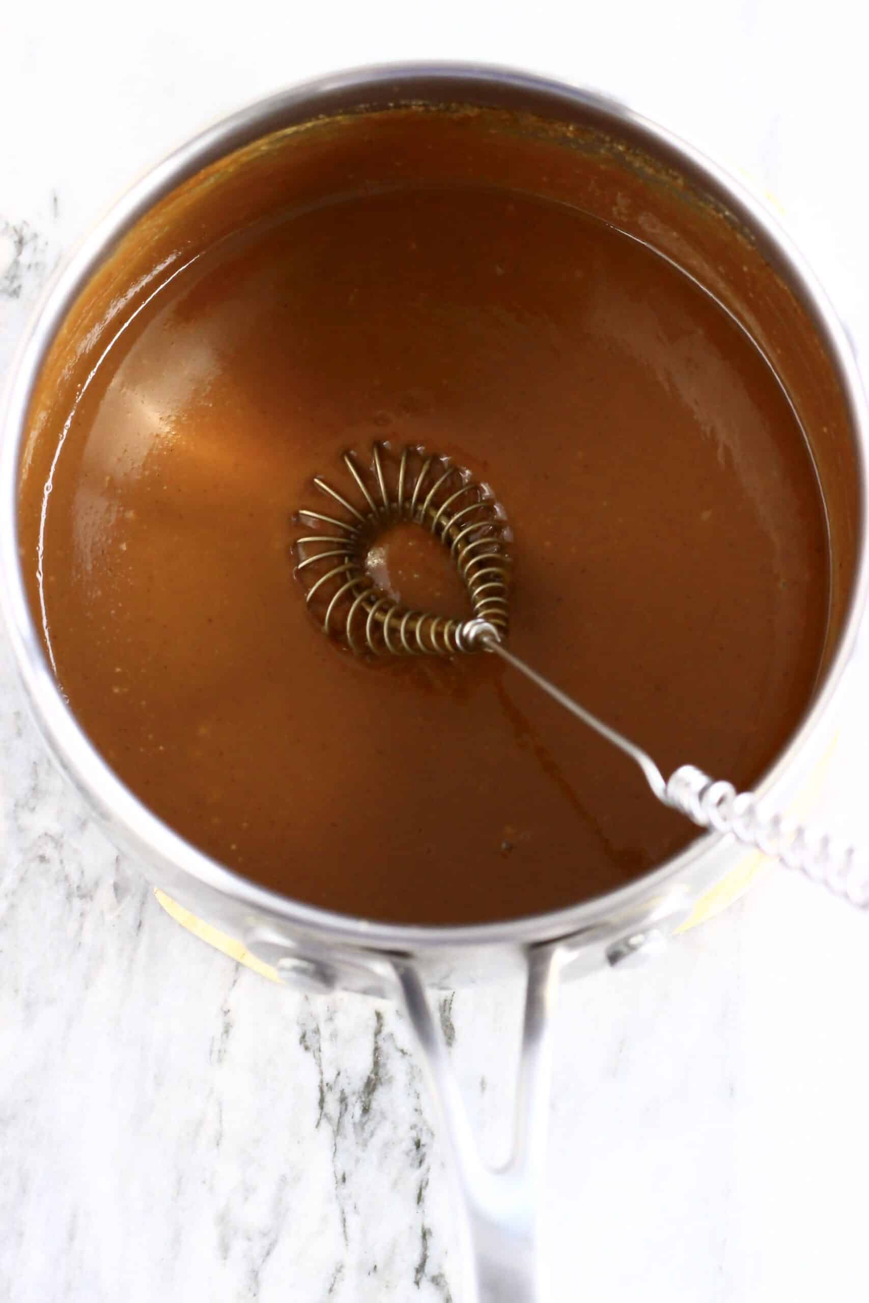 Vegan caramel sauce in a saucepan with a whisk