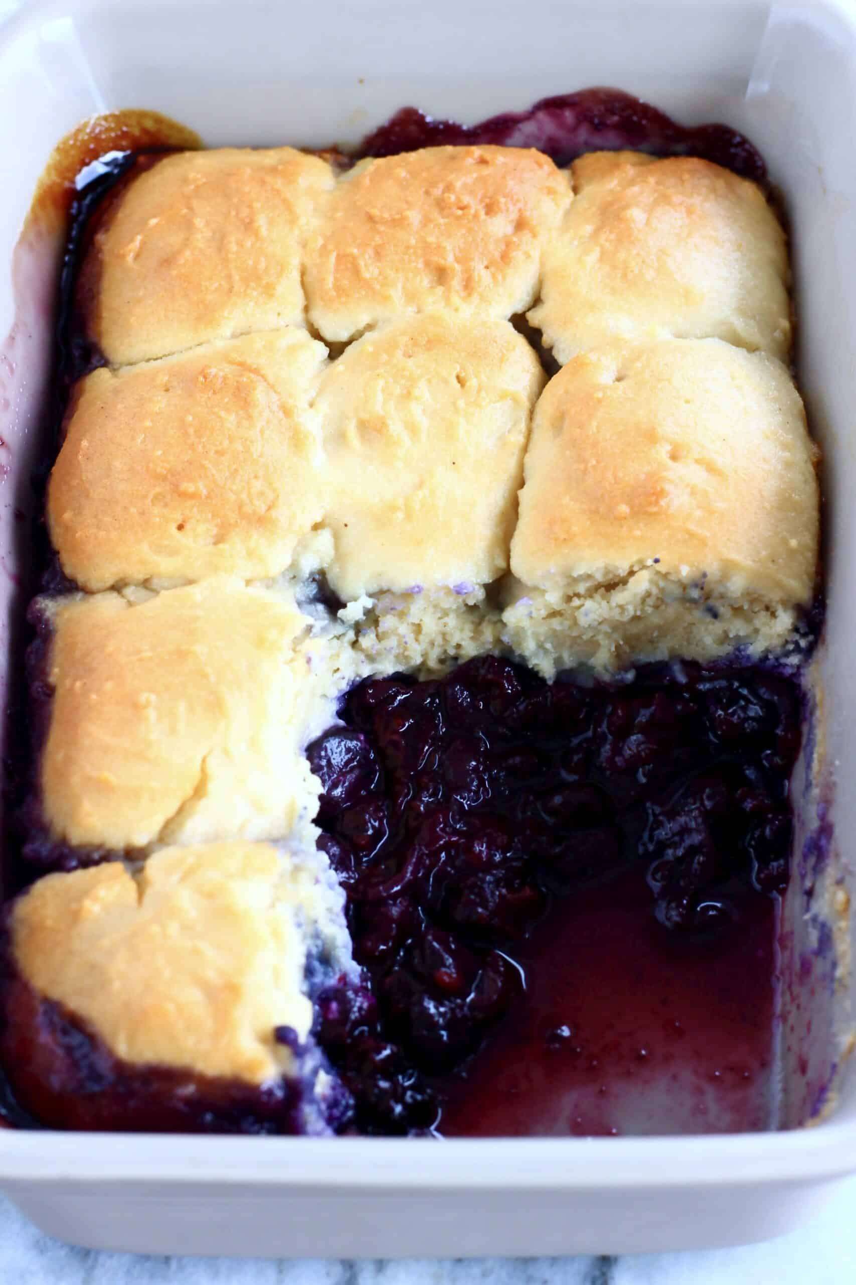 Vegan Blueberry Cobbler in a rectangular baking dish with a portion taken out of it